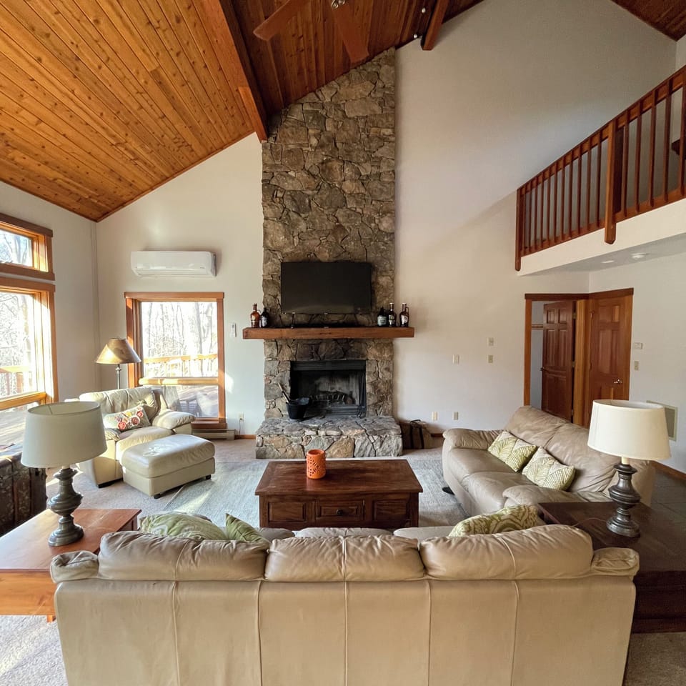 Main floor living room with wood burning fireplace and wilderness view.
