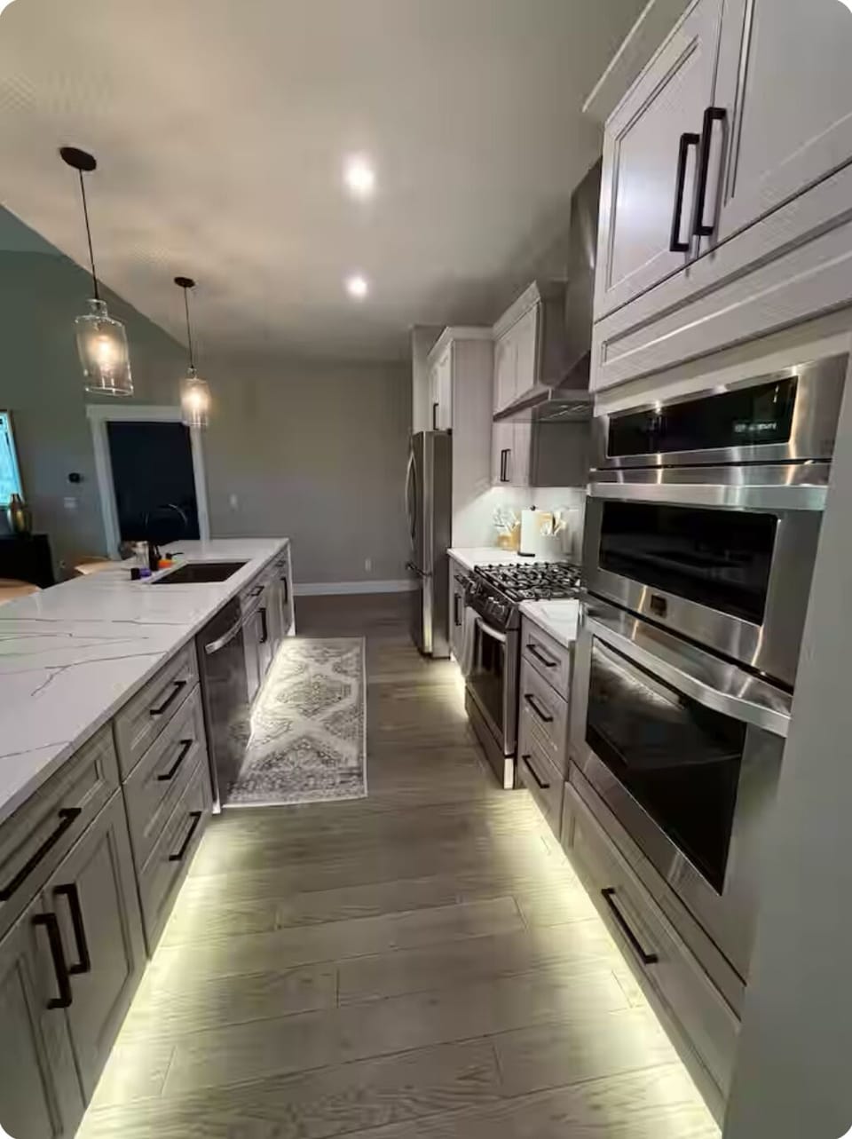 Comfortable and open galley kitchen with lighting.