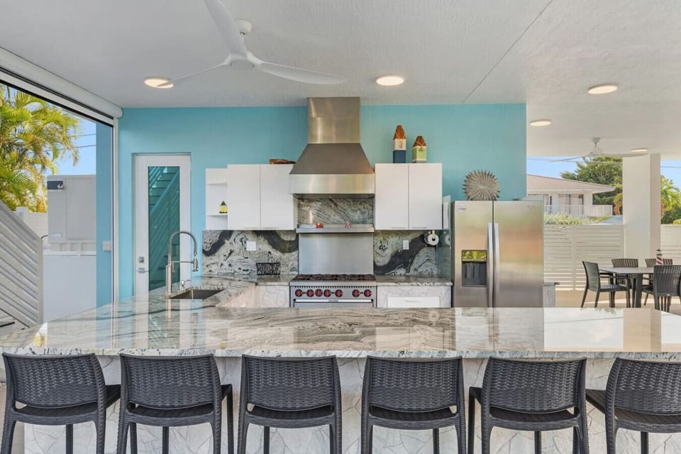 A spacious outdoor kitchen featuring commercial-grade appliances and seating for six at the bar—perfectly complementing the adjacent outdoor dining area for unforgettable cookouts.