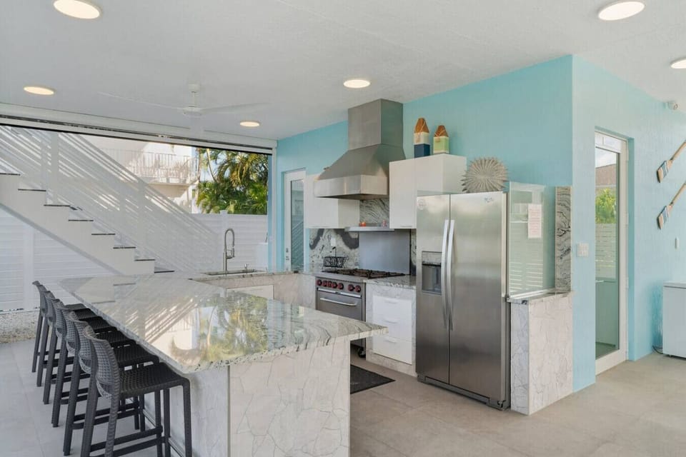 A spacious outdoor kitchen featuring commercial-grade appliances and seating for six at the bar—perfectly complementing the adjacent outdoor dining area for unforgettable cookouts.