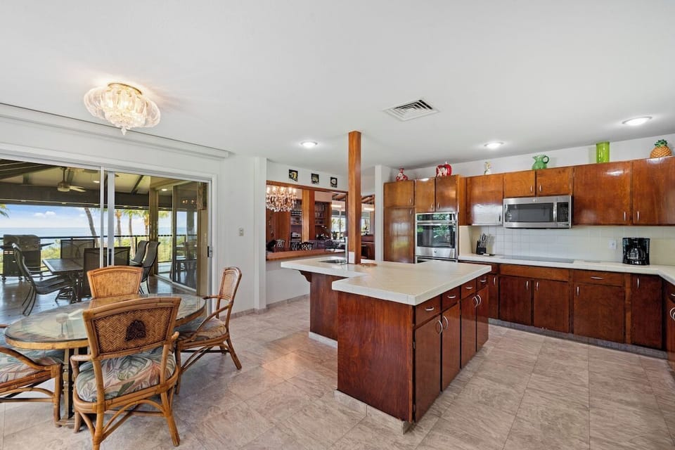 Open-concept kitchen with island, glass-top dining nook, and seamless access to outdoor balcony dining.