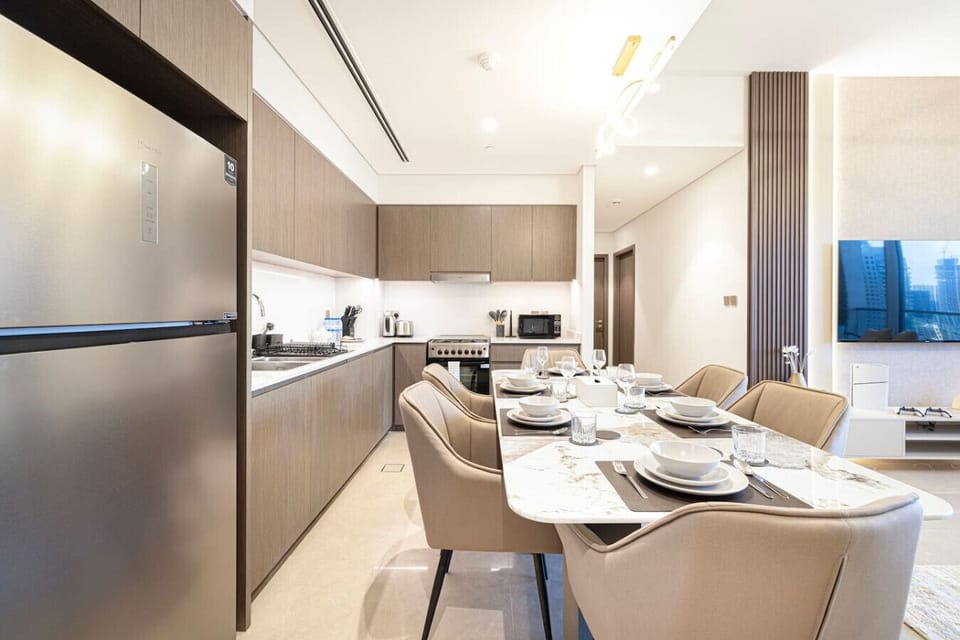 Enjoy meals at the elegant dining table, seamlessly connected to a fully equipped, modern kitchen. This stylish open-plan space offers the perfect setting for dining and cooking in your luxurious Downtown Dubai vacation home.