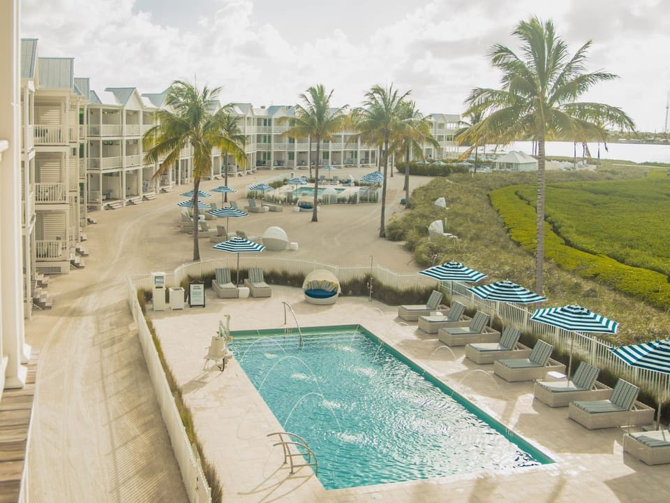 A tranquil retreat with palm-lined views and a refreshing pool, perfect for unwinding under the expansive sky.