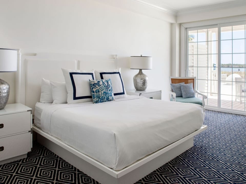 Serene bedroom with plush bedding, soft accents, and a private balcony for a relaxing retreat.