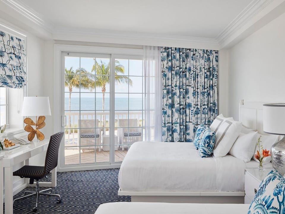 Light-filled bedroom with soft coastal touches and floor-to-ceiling windows overlooking the water.