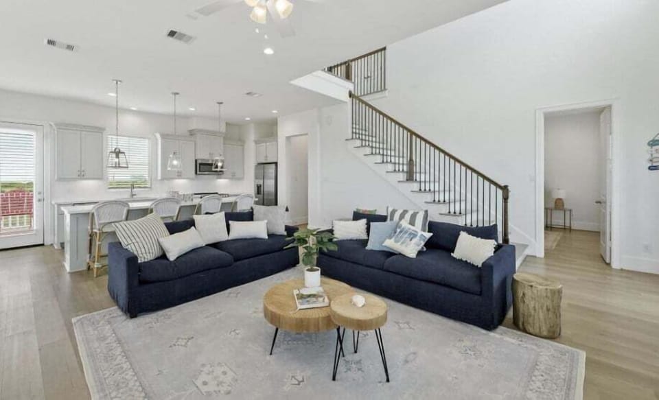 Elegant living room with modern furnishings and open staircase—bright and airy Galveston vacation home interior.