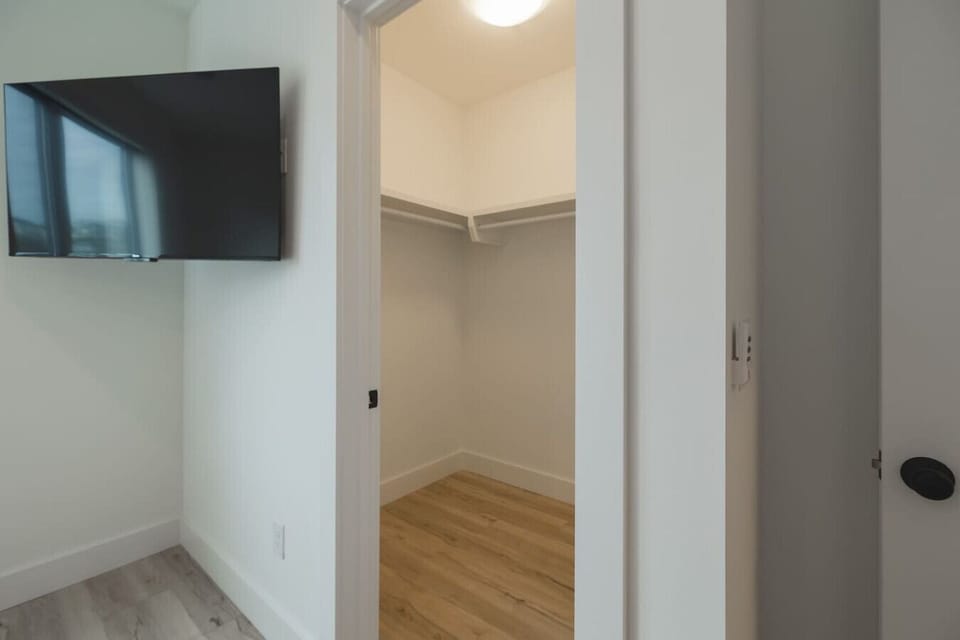 Spacious walk-in closet connected to a bedroom with a mounted TV.