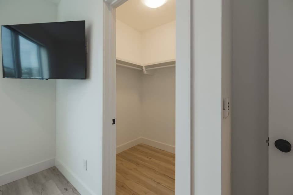 Spacious walk-in closet connected to a bedroom with a mounted TV.