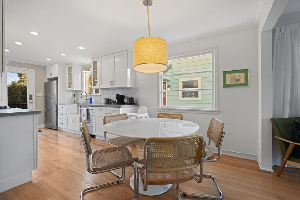 DINING: This bright dining area seats six and includes a high chair for little ones. A cozy pendant light and large windows create a warm, inviting atmosphere.