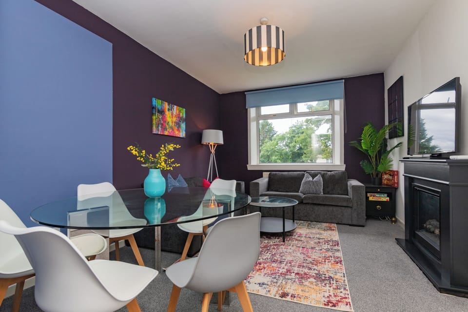 Relax in this spacious living room with natural light, cozy seating, and stylish decor perfect for family gatherings or quiet evenings.