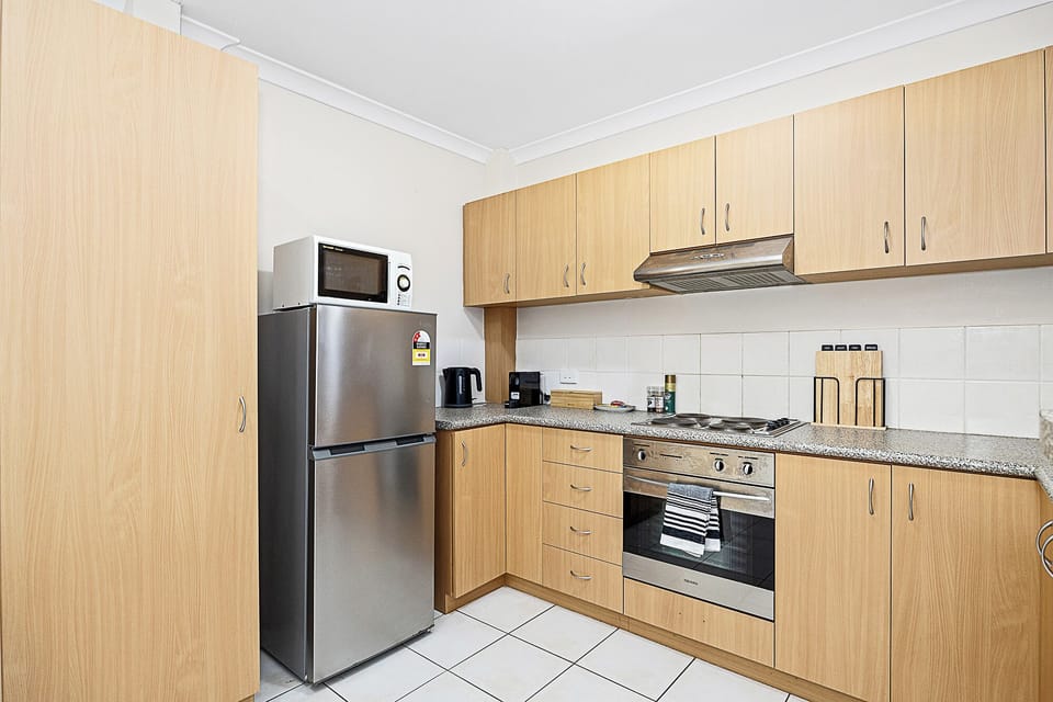 Prepare meals in a functional kitchen with a stainless steel refrigerator and modern appliances, offering convenience and style.