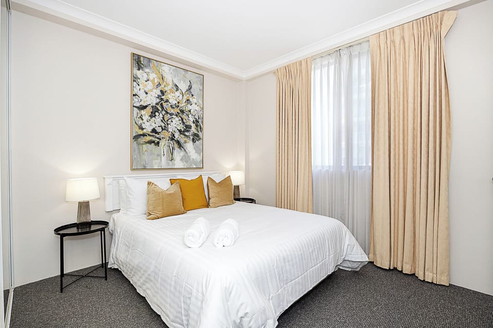 Unwind in a comfortable bedroom, featuring a king bed with plush bedding, ambient lighting, and a captivating artwork.