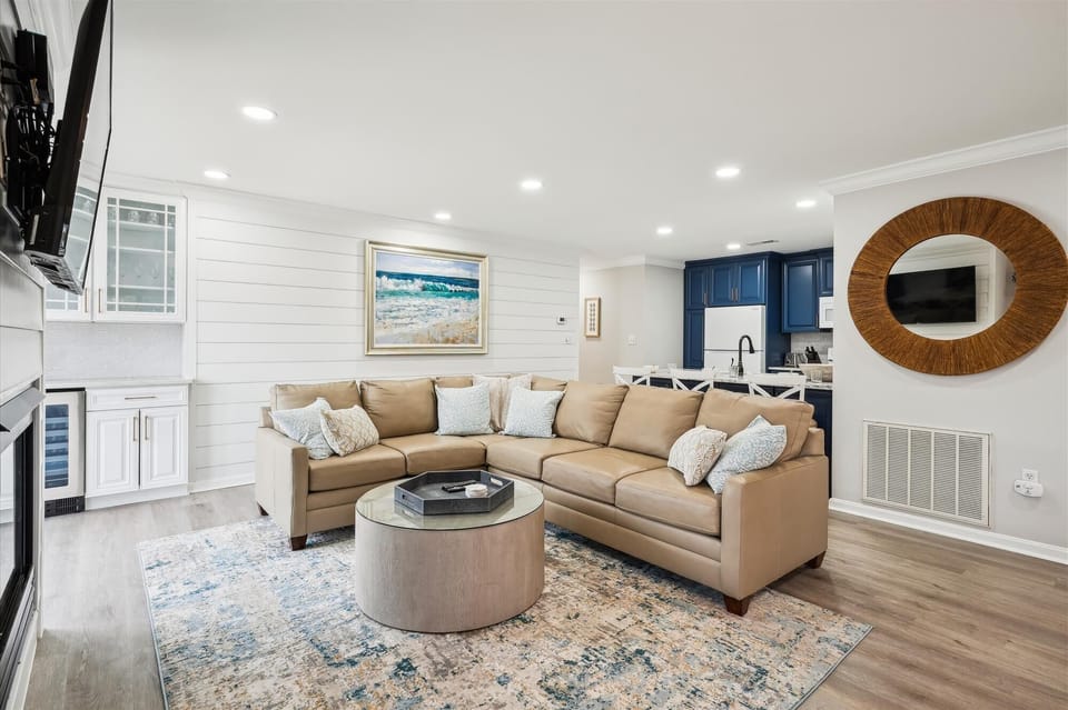 56152 Cypress Lake Circle - Living Area Overview - A comprehensive look at the redesigned living space, featuring a neutral sectional, coastal-inspired area rug, and modern wide-plank flooring. The open layout ensures a bright, social atmosphere that connects the main seating area to the kitchen and dining zones.