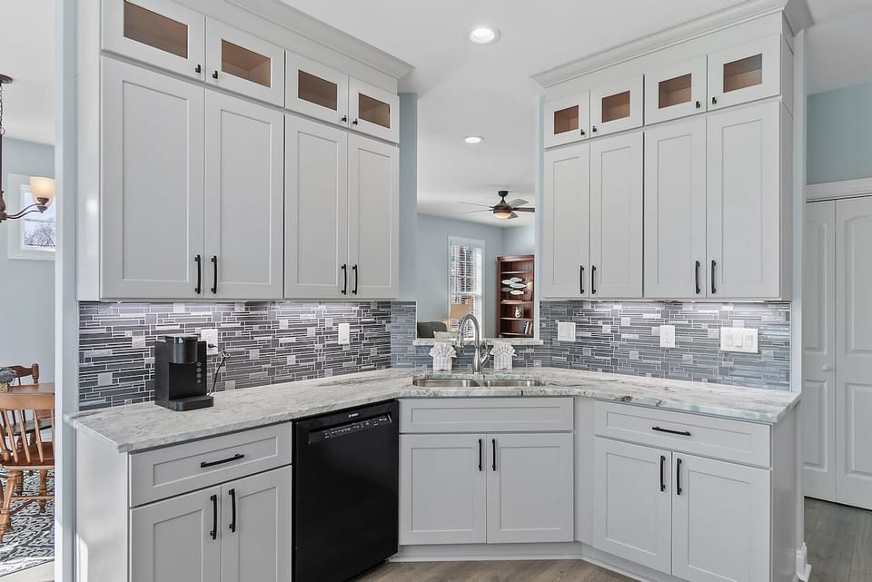 Your fully equipped kitchen features pristine white cabinetry, elegant granite counters, and stylish tile backsplash—perfect for preparing meals during your stay.