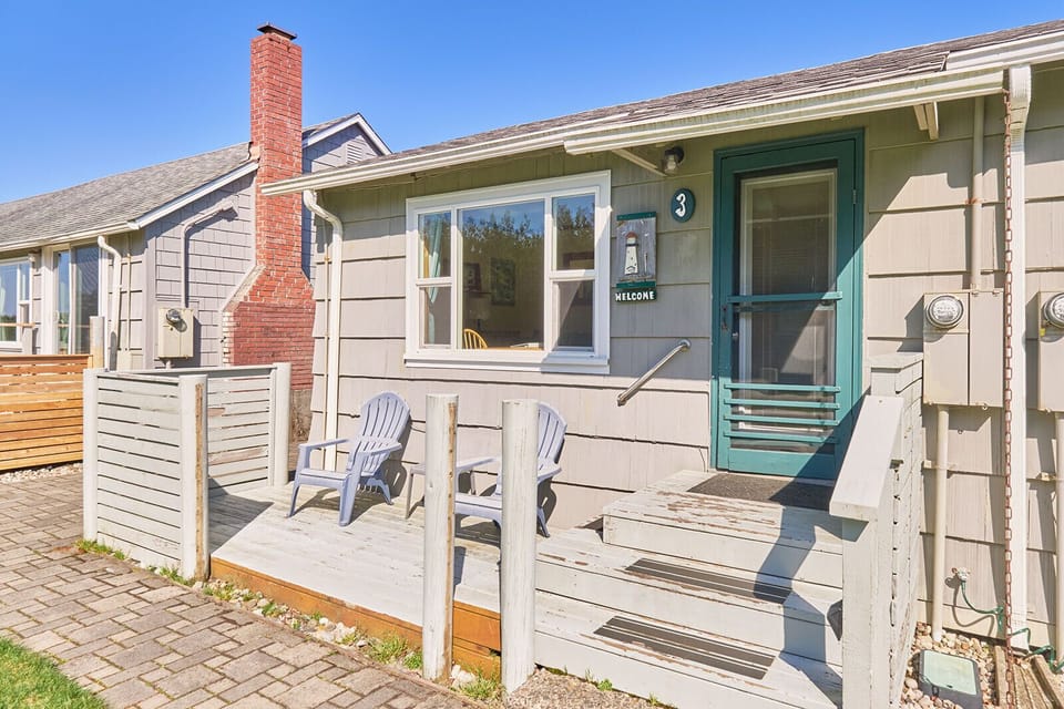 Back view of the cottage with access to a cozy patio—featuring outdoor seating, perfect for enjoying a quiet moment outdoors.