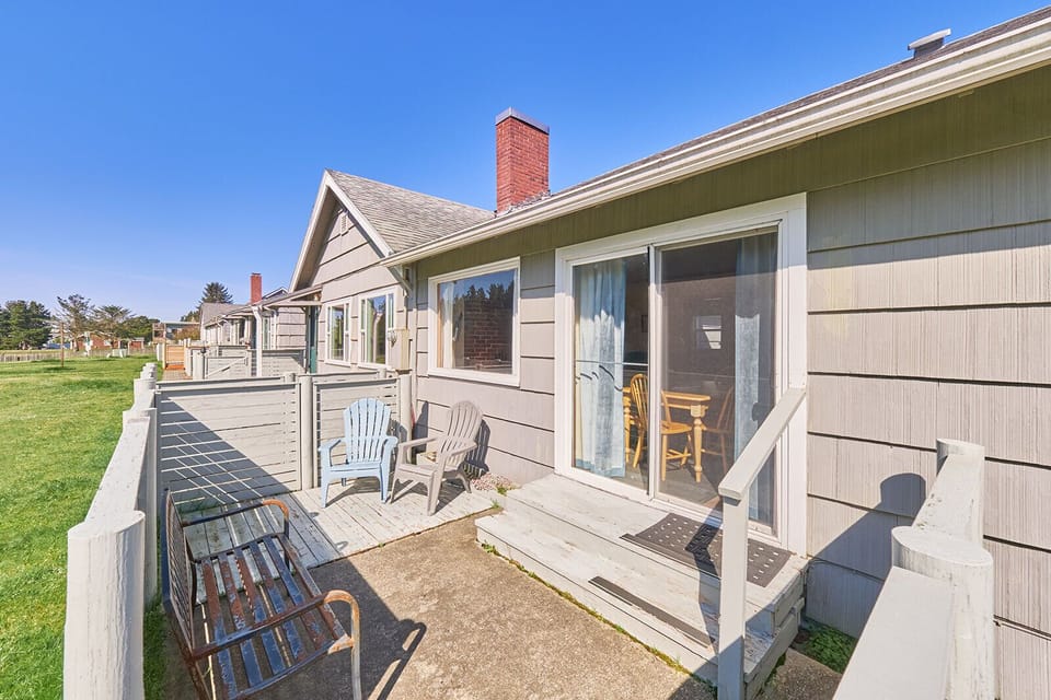 Back view of the cottage with access to a cozy patio—featuring outdoor seating, perfect for enjoying a quiet moment outdoors.
