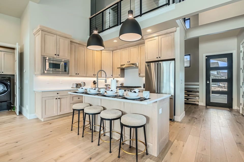 This chef-inspired kitchen features premium stainless appliances, sleek cabinetry, and a spacious island with seating for four. Perfect for morning coffee or casual dining in a bright, modern setting.