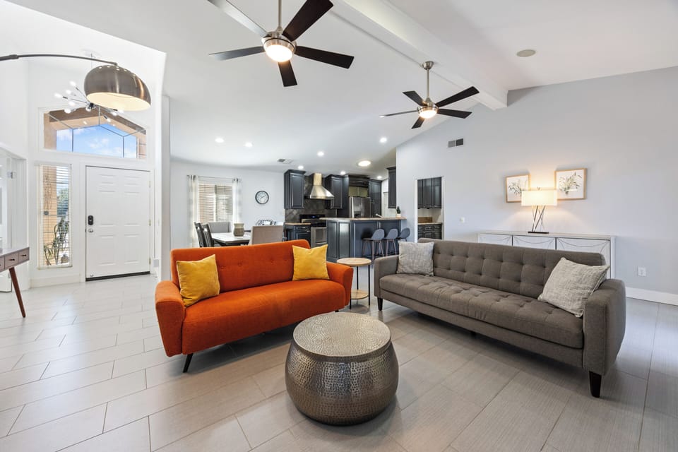 Bright living space with vibrant orange sofa and open sightlines to the kitchen.