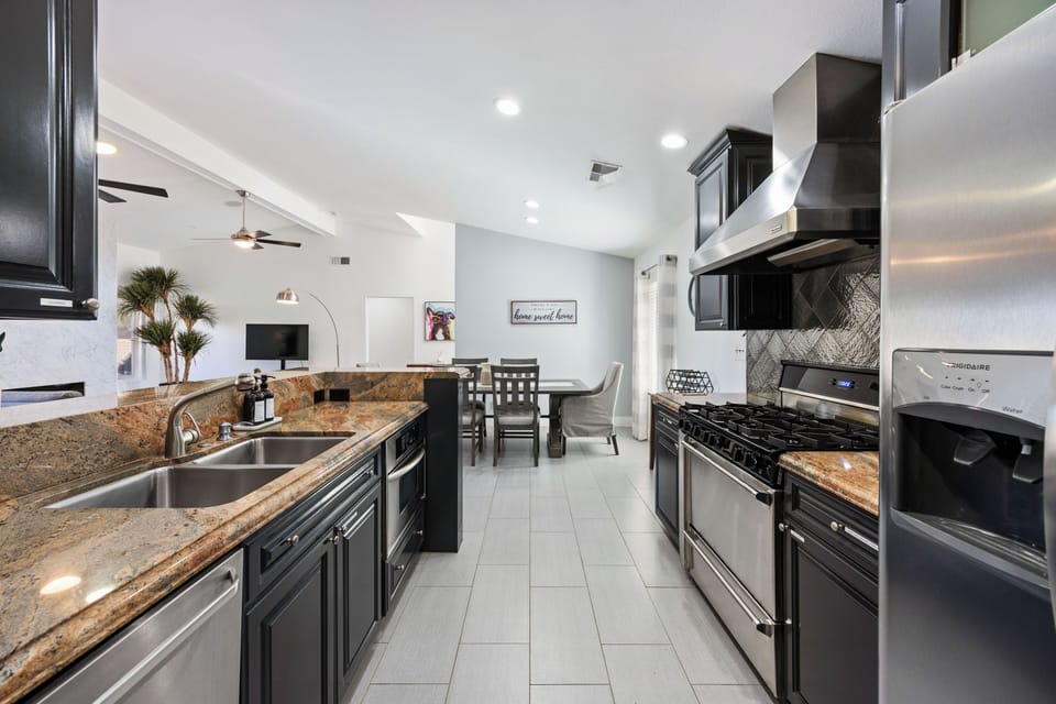 Sleek black galley kitchen with granite counters and stainless appliances.