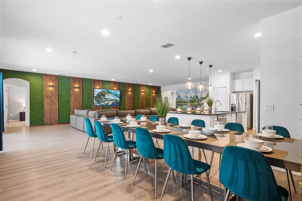 - Gather at the long dining table with seating for large groups  
- Stylish teal chairs and modern decor enhance family meals  
- Open-concept dining flows into kitchen and living area