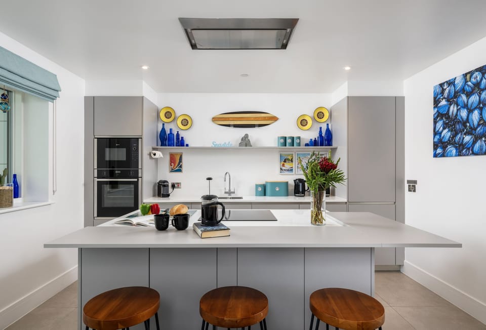 1 Cliff Edge, Newquay: Kitchen with modern appliances, including a wine fridge, induction hob, and remote-controlled extractor fan
