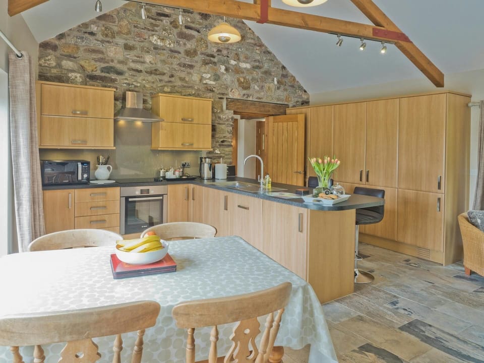 Living area: dining table with four chairs; kitchen with built in oven and hob, microwave, kettle and breakfast bar