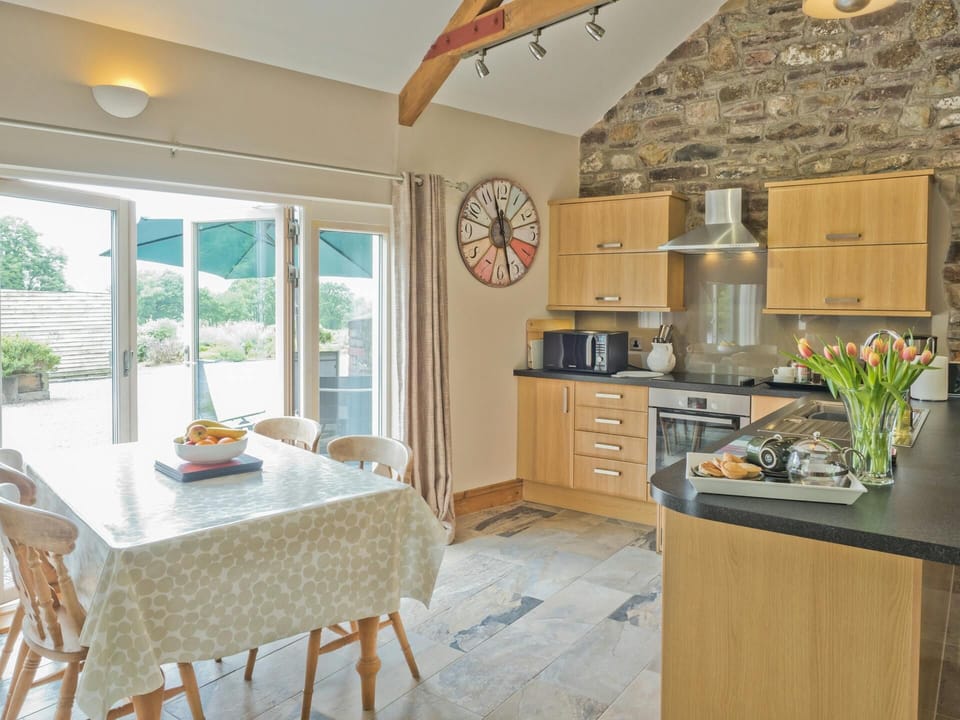 Living area with table and four chairs, fitted kitchen and breakfast bar