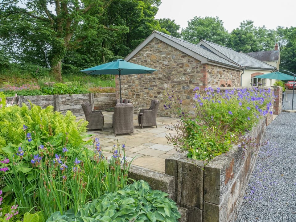 Large enclosed patio area with circular table, four chairs and parasol