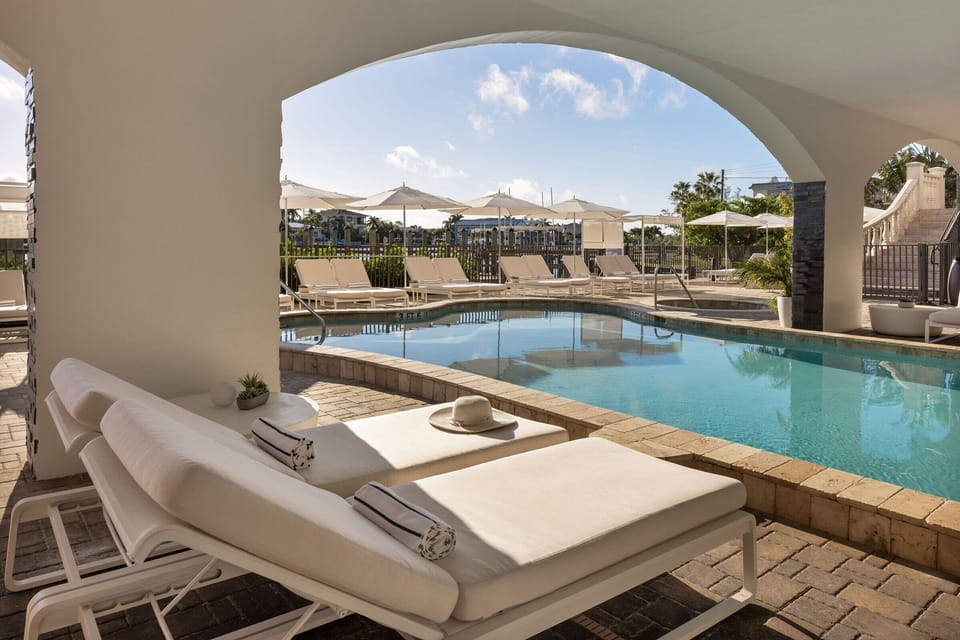 Unwind poolside under breezy arches with serene, sunlit views.