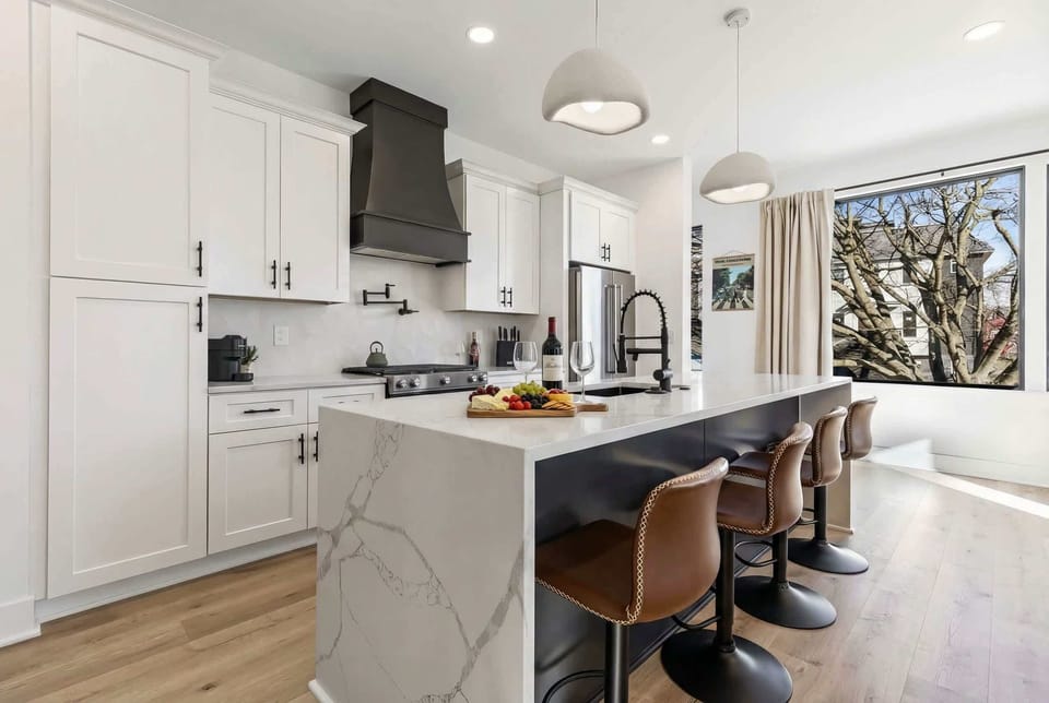 Kitchen island with bar seating opens to the game room, so the host stays connected to the group while dinner comes together