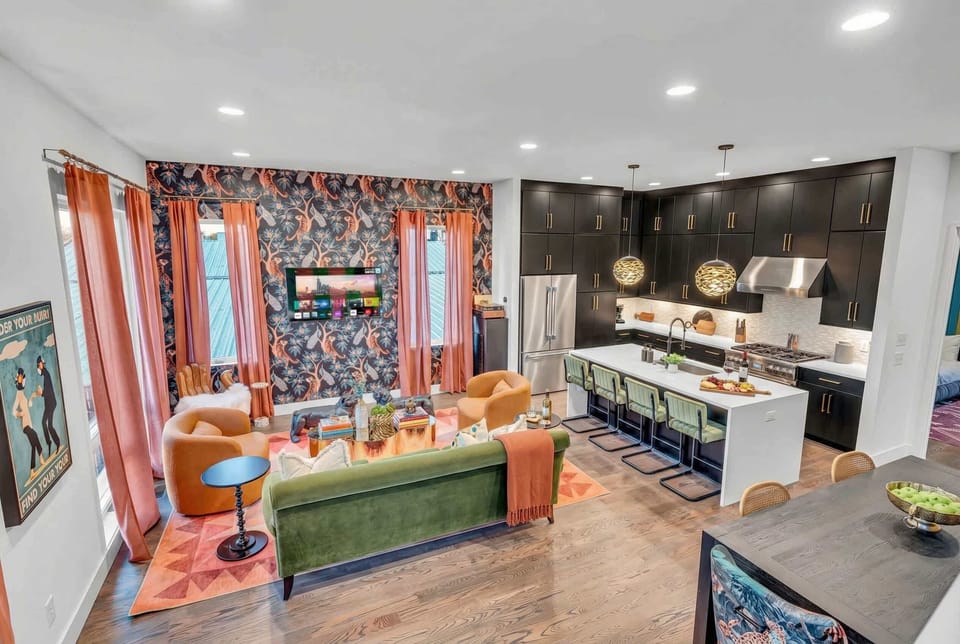 The open-plan living room keeps everyone in the conversation, with a green sofa, armchairs, and a kitchen island where the cook never feels left out during your Nashville group getaway