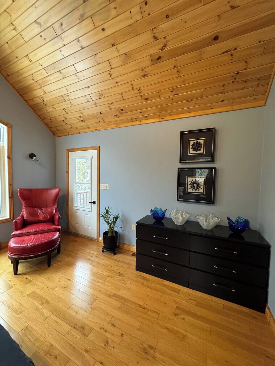 Bedroom 1: Relax with a book in this inviting corner featuring a lounge chair, dresser, and natural light—ideal for quiet moments away from the bustle. 