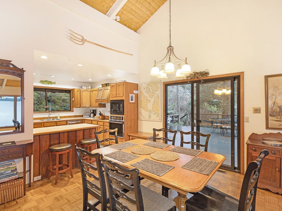 Open dining area, table sits 6 people plus 2 additional stools at the bar top. Sliding glass door leads to the large, open deck and bbq.