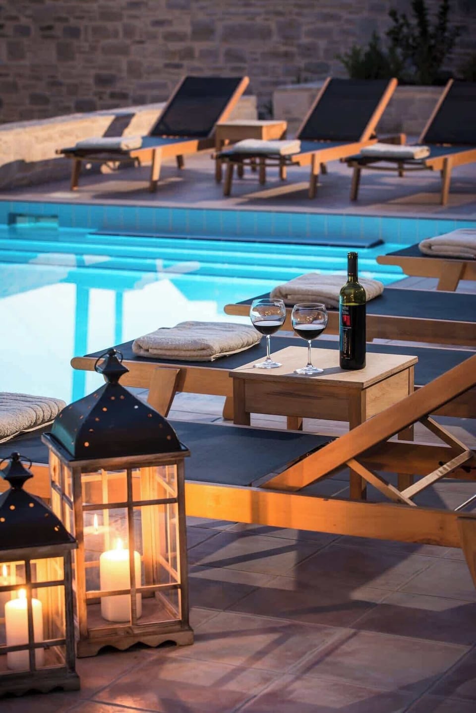 Phaistos Villas – Wine by the Poolside – Enjoy a glass of wine as the sun sets over the peaceful pool and stone surroundings.