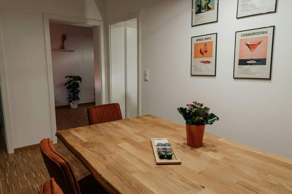 Inviting dining space with warm wood tones and vintage-style cocktail prints – the open layout enhances brightness and flow.