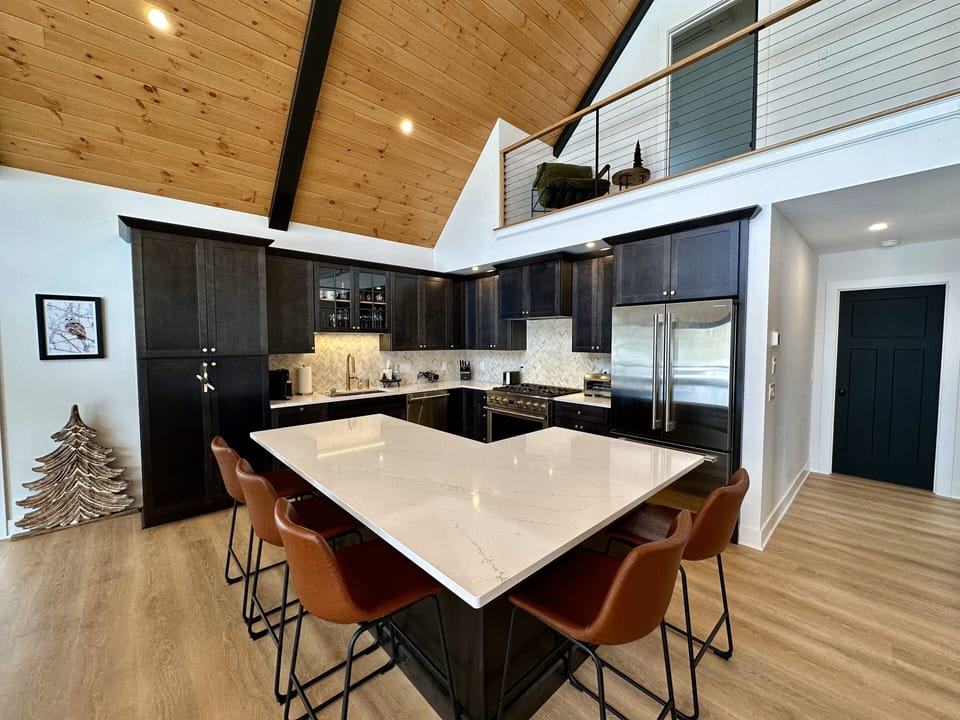 A chef's kitchen complete with large island, quartz countertops & GE appliances.