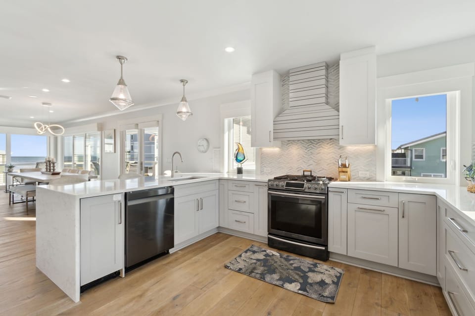 Open Luxury Fully Equipped Kitchen on the 2nd Floor with Beautiful White Cabinetry, Stainless Steel Appliances, and Quartz Countertops