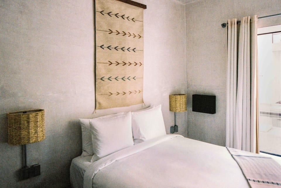 Sink into crisp linens beneath warm, woven bedside glow.