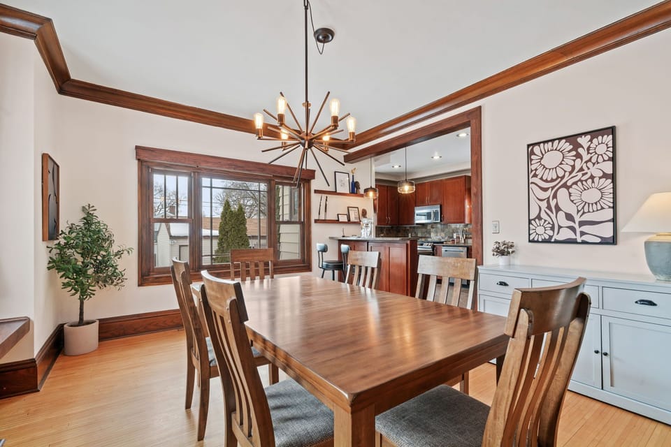 Gather around your spacious dining table beneath warm lighting, sharing memorable meals while rich wood details create an elegant, welcoming atmosphere.