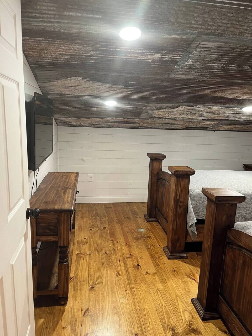 Rustic charm meets modern comfort in this cozy loft bedroom. Warm wood tones and a weathered ceiling create a unique ambiance.
