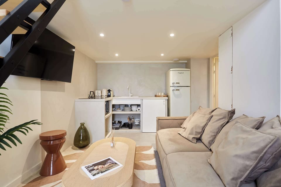 Salon avec canapé lit (deux personnes), smart tv, coin repas et cuisine ouverte équipée