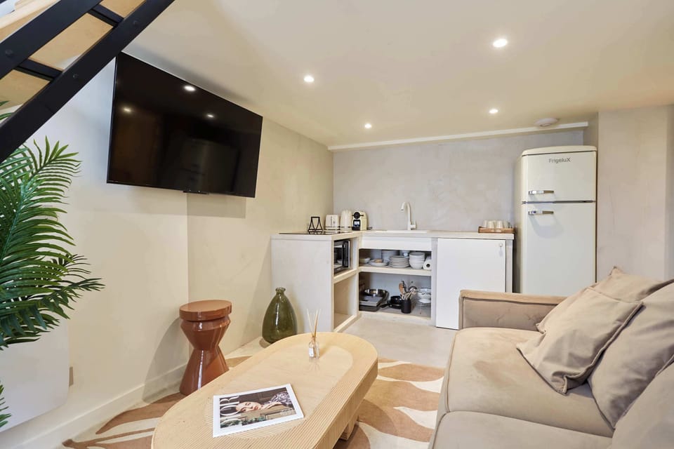Salon avec canapé lit (deux personnes), smart tv, coin repas et cuisine ouverte équipée