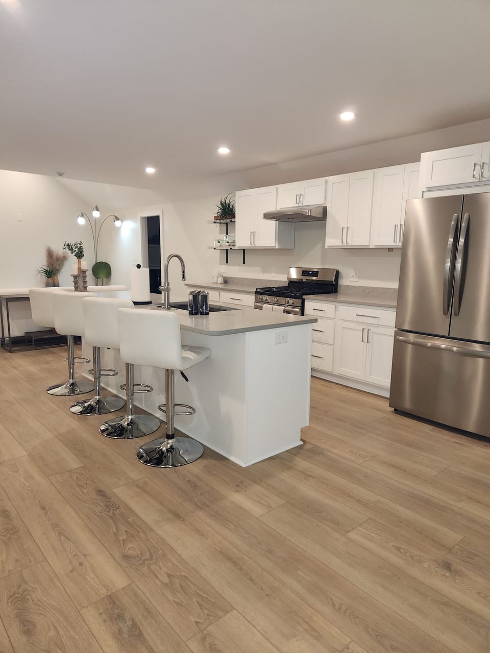 Stainless steel appliances, white leather bar stools, and large center island