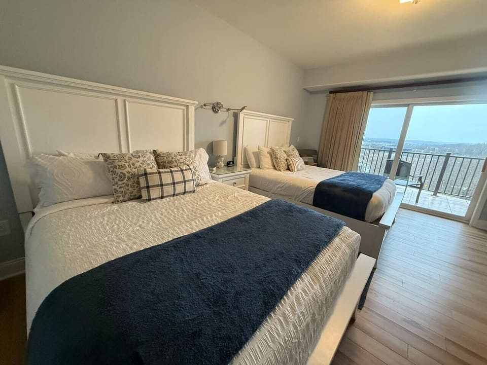 Double-queen retreat with plush bedding, built-in storage beds, and a private balcony overlooking the lake