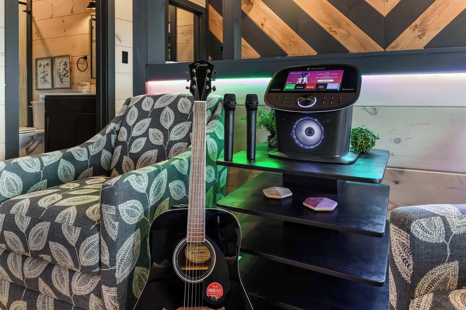 Cozy seating area with a guitar and karaoke machine for entertainment.