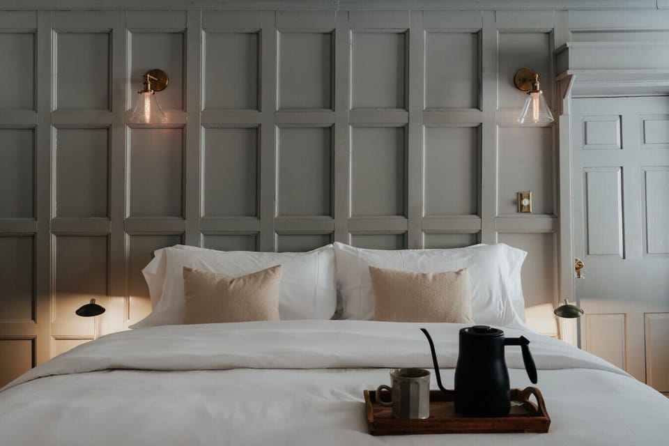 Elegant and inviting, the Austen Room’s king-size bed is dressed in crisp white linens, offering a serene retreat. Warm lighting and classic wall paneling create a timeless ambiance, perfect for unwinding after a day of exploring.