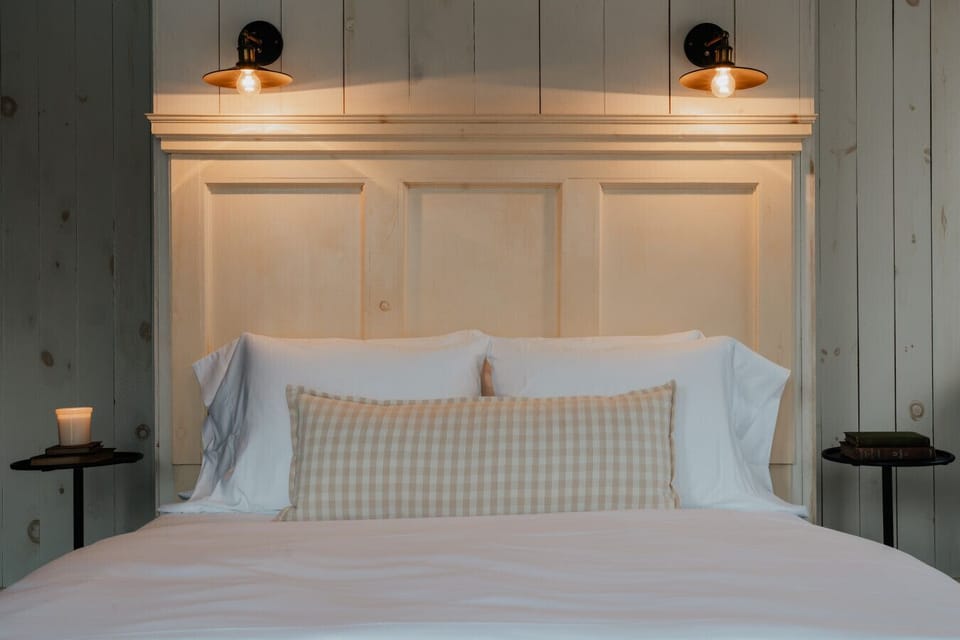 The Dickinson Room offers a peaceful retreat with a plush queen-size bed, soft lighting, and rustic panel walls. A cozy sanctuary for a restful night’s sleep.
