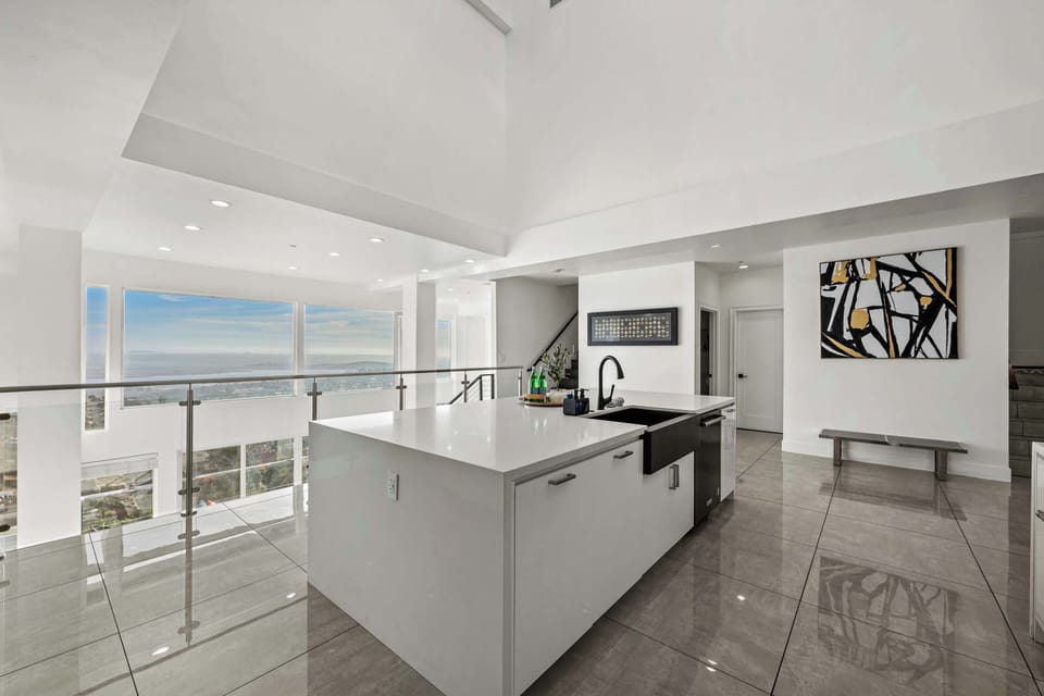 This elegant open-concept kitchen features a sleek white island, contemporary decor, and breathtaking views. Ideal for cooking and entertaining, it provides a stylish and welcoming space for memorable gatherings.