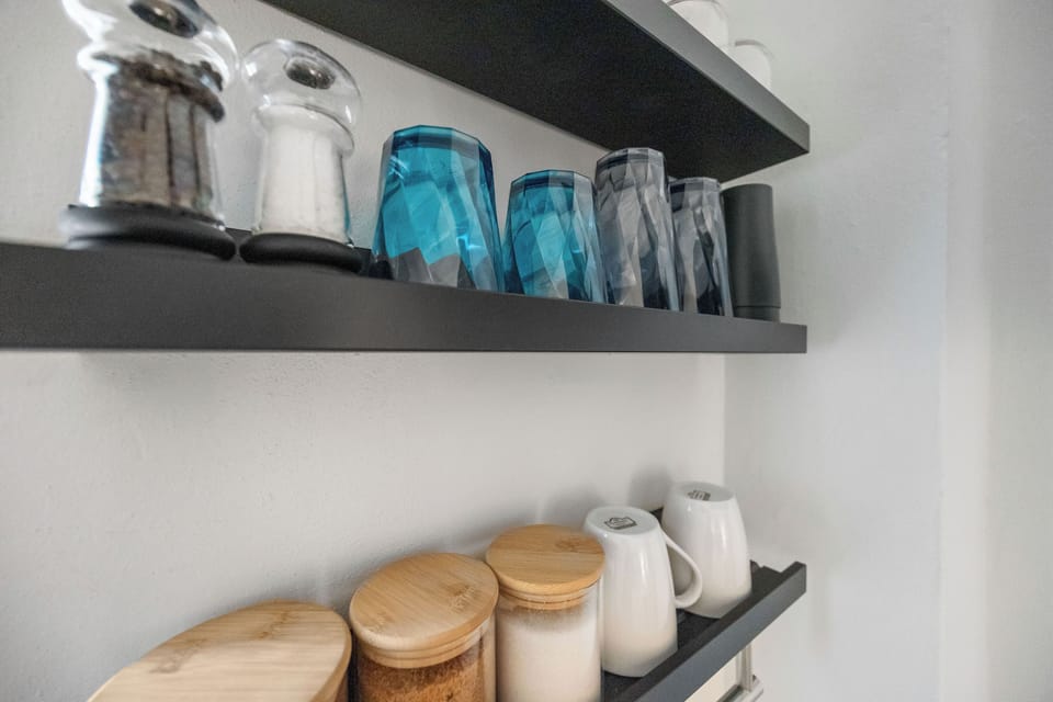  Imagine effortlessly organizing your essentials in this beautifully designed space.  Crisp white walls provide a fresh backdrop for your personal style, while the striking black shelving offers a contemporary touch and clever storage.