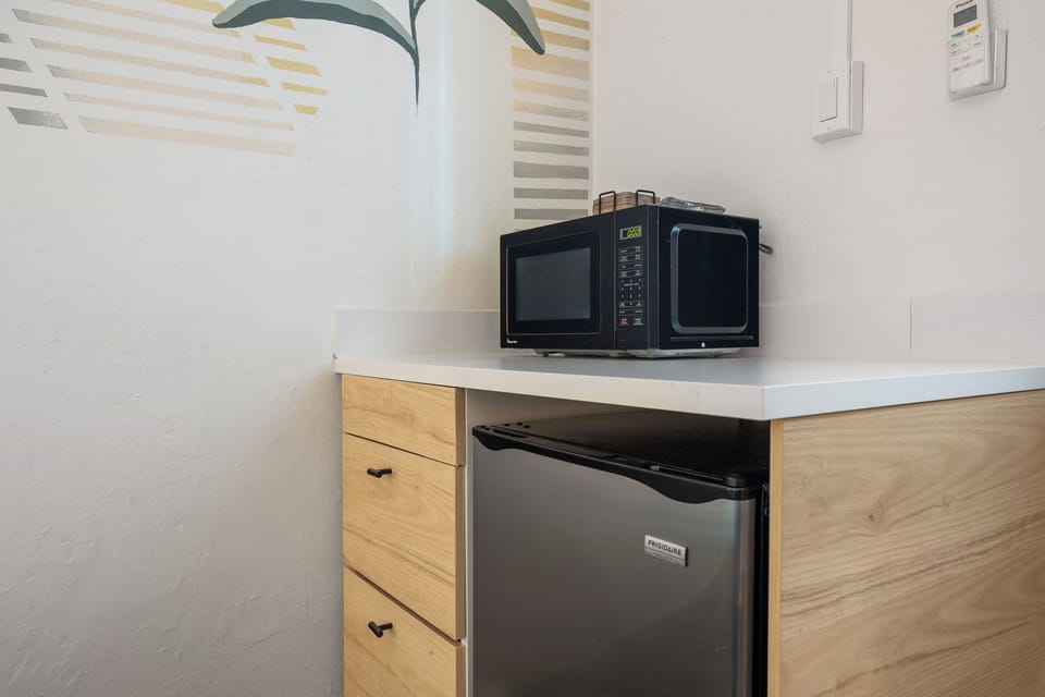 Whip up your favorite snacks and meals effortlessly in this sleek, minimalist kitchen, complete with a compact oven and handy mini fridge for all your essentials.